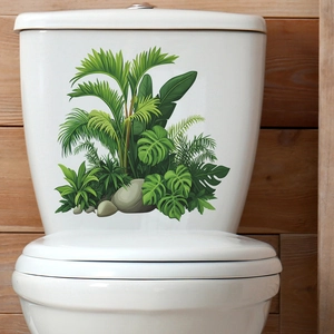 Detail of tropical monstera leaves and pebble stickers on a white ceramic toilet tank