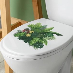 Tropical monstera leaf sticker applied on a white toilet lid in a clean bathroom
