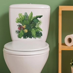 Detail of tropical monstera leaf stickers applied to a white ceramic toilet tank surface