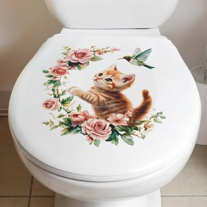 Détail d'un autocollant chat orange et fleurs roses sur le couvercle des toilettes