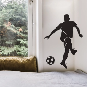Dynamic black silhouette of a soccer player wall decal in a modern bedroom setting