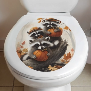 Detail view of cartoon raccoons and pumpkins decal on a white toilet lid cover