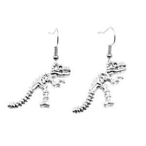 Macro detail of silver dinosaur skeleton earrings with fish hook wires and metallic finish