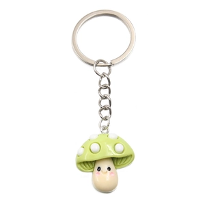 Close-up of a cute green resin mushroom pendant with a smiling face and metallic keychain