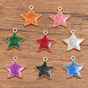 Dettaglio di ciondoli a forma di stella con smalto glitter e montature in metallo dorato DIY