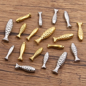Detailansicht von Fisch-Anhängern in Gold und Silber mit Schuppen-Textur auf Holz