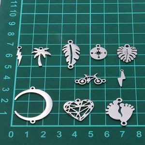 Assorted stainless steel charms including lightning and moon on a green measuring mat