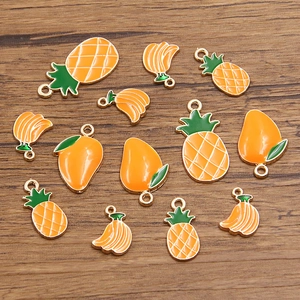 Macro shot of KC gold enamel tropical fruit pendants on a dark wood background