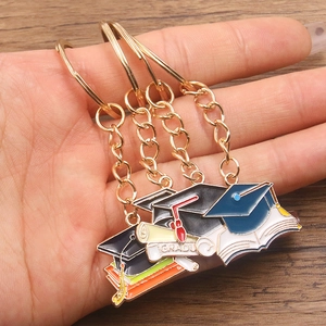 Graduation keychain set featuring doctoral cap, scroll and book charms in gold alloy