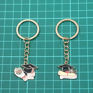 Gold-tone enamel graduation keychains featuring mortarboard cap and diploma scroll