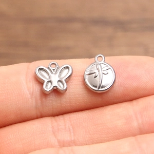 Micro shot of butterfly and dragonfly stainless steel charms on a finger tip for DIY jewelry