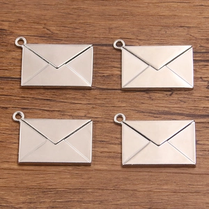Detailed macro view of four antique silver envelope charms with hanging loops for DIY crafts