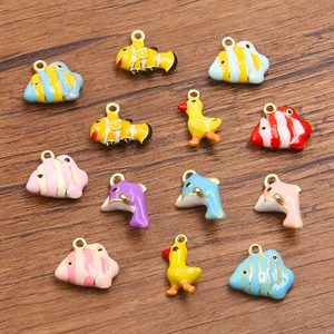 Colorful DIY alloy charms with dolphin and fish pendants on a wooden background
