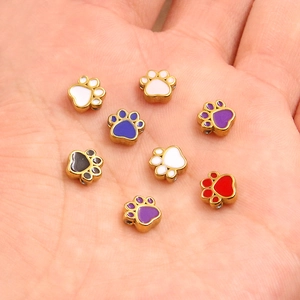 Golden stainless steel enamel animal paw beads for DIY jewelry making displayed on a hand