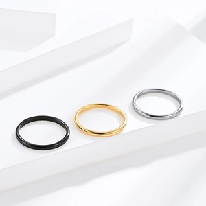 Minimalist tungsten steel rings in black, gold, and silver finishes on white blocks