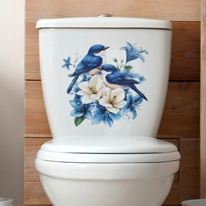 Stickers oiseaux bleus et fleurs de lys sur réservoir de toilettes blanc dans la salle de bain
