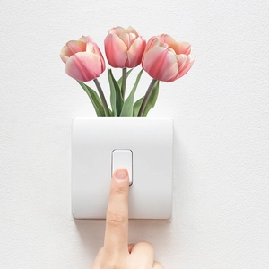 Detailansicht eines weißen Lichtschalters mit Tulpendekoration und Handbedienung