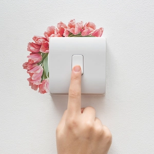 Minimalistischer weißer Lichtschalter matt mit rosa Tulpen auf weißem Hintergrund