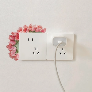 Detail einer mattweißen Doppelsteckdose mit Tulpen-Wandaufkleber und USB-Ladegerät-Zubehör