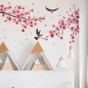 Detailed view of pink cherry blossoms and birds wall decal in a cozy bedroom