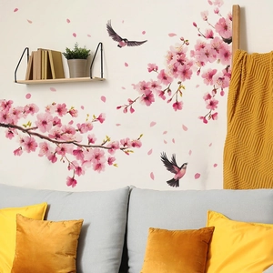 Detail of pink cherry blossom wall stickers with birds above a modern sofa