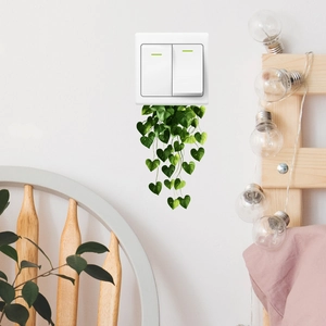 Green hanging leaf wall stickers decorating white walls and power switches in a bedroom