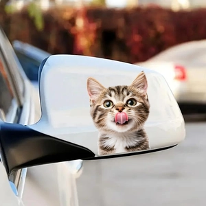 Cute tabby kitten licking nose sticker applied to a white car side rearview mirror