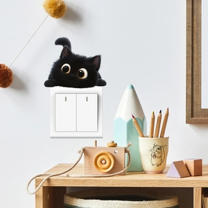 Close-up of a cute black peeping cat sticker applied on a white wall light switch