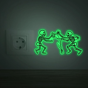 Luminous green skull wall sticker glowing in dark near power outlet for home decor