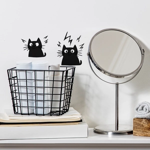 Detail of cartoon black cat wall stickers on a white wall near a vanity mirror