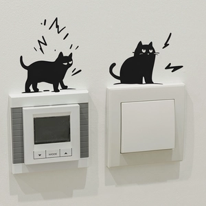Close-up of two cute black cat silhouettes decorating a white light switch panel