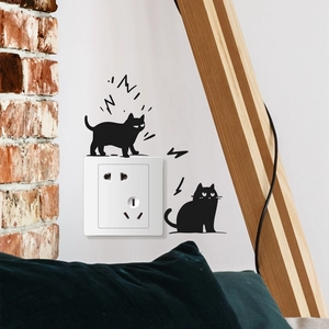 Detail of two black cat silhouettes wall stickers applied around a white light switch