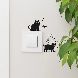Detail of cartoon black cat wall stickers decorating a white light switch on a neutral wall