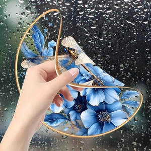 Detail of static window film with blue floral dragonfly design on raindrop glass