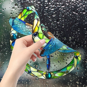Detail of stained glass style dragonfly window film applied on rainy glass surface