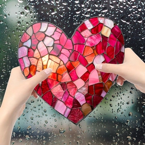 Colorful stained glass heart suncatcher decor held against a rainy window background