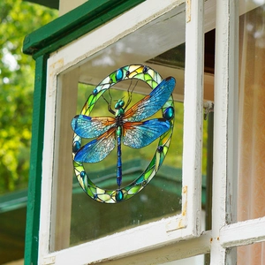 Detailed close-up of a handmade stained glass dragonfly suncatcher hanging on a window