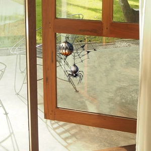 Halloween spider and orange ornament static window cling on a glass pane with garden view