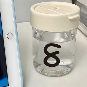Transparent water bottle with cream cap and black number 8 print on white office desk