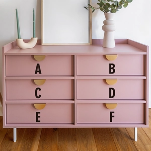Modern pink 6-drawer dresser with golden handles and white metal legs in a home setting