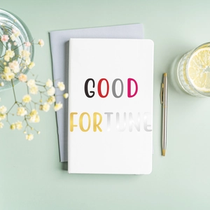 DIY minimalist white notebook featuring colorful Good Fortune letter stickers and artistic design