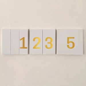 Detailed view of matte cream decorative wall tiles with metallic gold number sequence