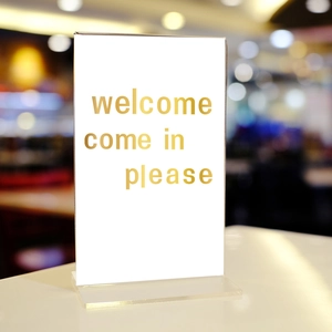 T-shaped transparent acrylic display stand with gold lettering on white card