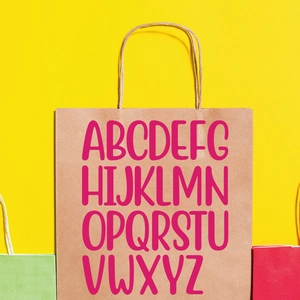 Brown kraft paper gift bag featuring bold pink alphabet letters A-Z on a yellow background