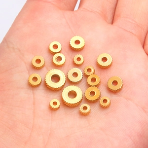 Golden stainless steel gear spacers for DIY jewelry making held in a hand for scale