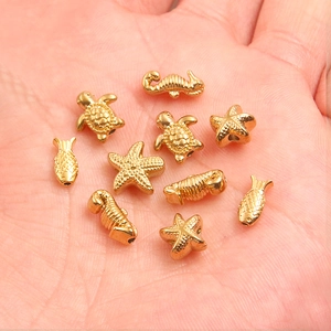 Gold stainless steel ocean charms including starfish and seahorse held in hand