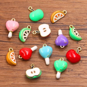 Colorful DIY fruit and heart enamel pendants on wood background for jewelry making
