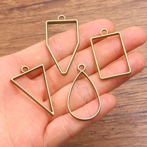 Antique bronze DIY open bezels in geometric shapes held in palm for scale