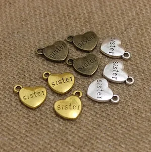 Close-up of heart-shaped sister charms in gold, silver, and bronze on burlap fabric