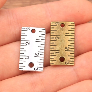 Detailed macro view of silver and bronze alloy ruler pendants with engraved scale markings